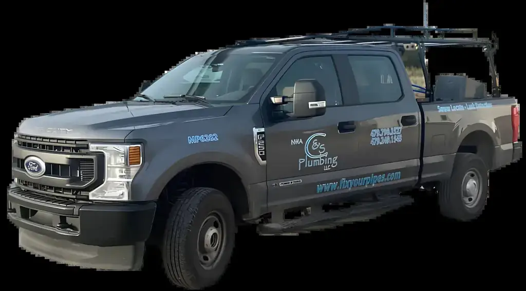 A charcoal Ford pickup with NWA C&S Plumbing lettering on the door, shown on a black ground