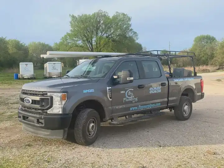 A charcoal NWA C&S Plumbing pickup with PVC on the rack and two branded enclosed trailers behind it