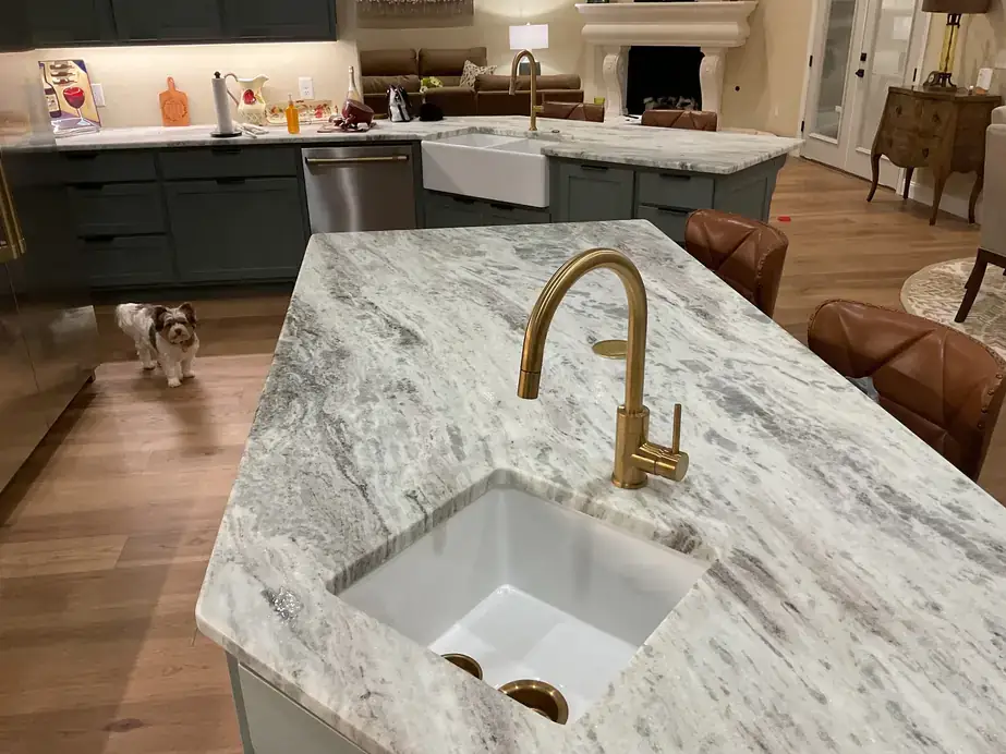 Kitchen remodel with a brushed gold faucet over an undermount sink in a marble island