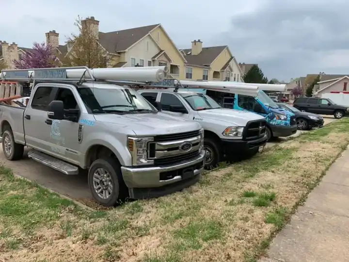 A line of silver NWA C&S Plumbing pickups and the wrapped van parked on grass