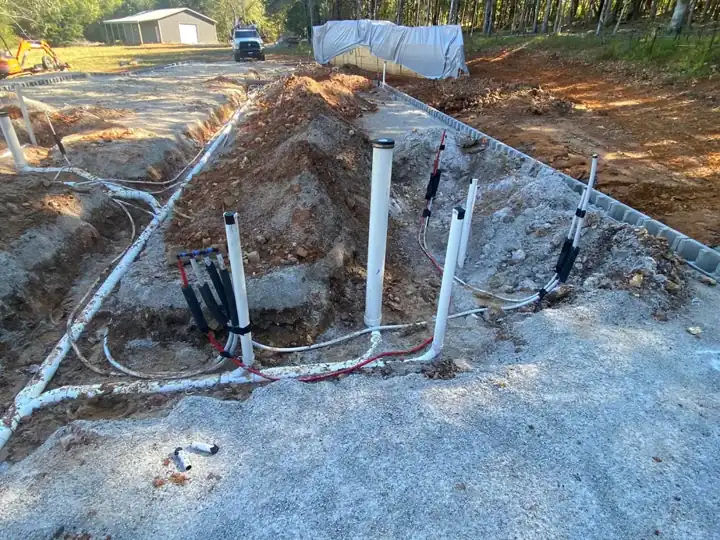 White PVC risers and red and blue PEX stubs rising out of compacted gravel inside a block stem wall on a new build
