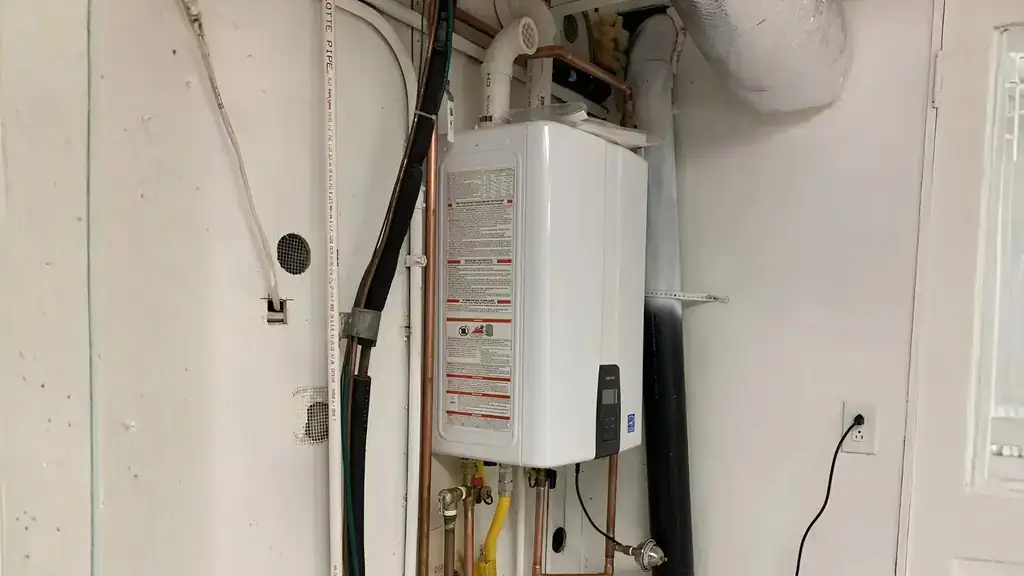 Tankless water heater freshly mounted on a white wall with gas and copper connections