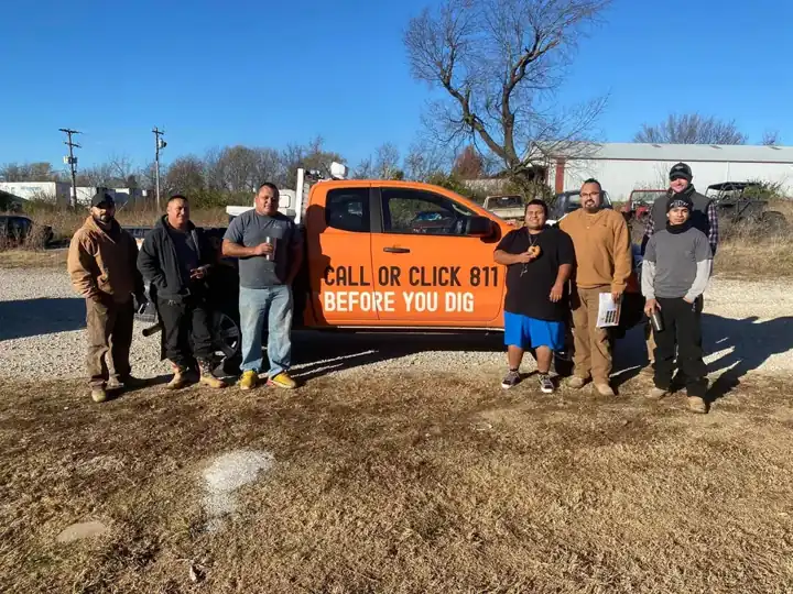 The NWA C&S Plumbing crew standing in a gravel lot in front of an orange Call 811 pickup