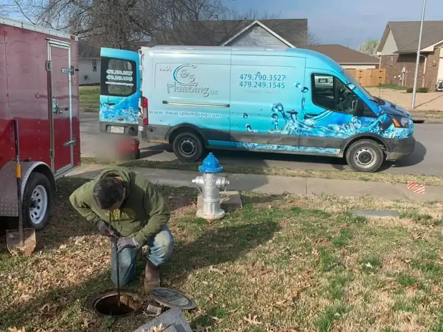 C&S plumber opening a sewer cleanout in a front lawn beside the company's wrapped van